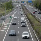 Tráfico en autopista, coches circulando. ¿Cuánto vale el peaje de Madrid? La carretera se ve con vegetación a los lados.