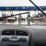 Fila de coches en un día lluvioso en los peajes de España. El coche se acerca a las cabinas de pago.