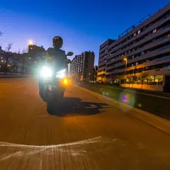 Motociclista con luces potentes de noche. Para no deslumbrar, es importante ajustar la altura de los faros y usar luces de baja intensidad cuando sea posible.
