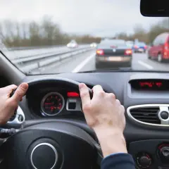 Manos al volante en carretera con tráfico. Mantener una distancia de frenado segura depende de la atención.