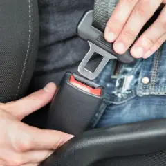 Persona abrochando el cinturón de seguridad en un coche. En un turismo es obligatorio utilizar los cinturones de seguridad.