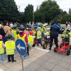 Niños con chalecos reflectantes participan en juegos de educación vial, aprendiendo normas de tráfico con bicicletas y coches de pedales.