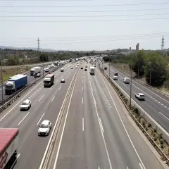 Tráfico intenso en la ap7 Girona, con camiones y coches circulando por la autopista bajo un cielo despejado.
