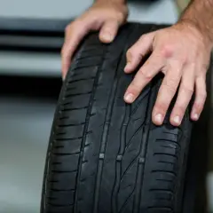 Manos sostienen una rueda de coche. Averigua cuanto se tarda en cambiar una rueda.