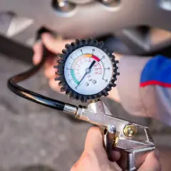 Manómetro de presión de neumáticos conectado a una rueda. Muestra cómo ver la presión correcta para tus neumáticos.