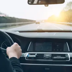 Conduciendo por la autopista, el sol brilla al atardecer. El navegador muestra la ruta, anticipando el pago del vía t peaje.