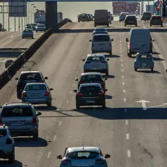 Tráfico denso en autopista, con coches y furgonetas circulando. Se observa señal de tráfico con **mínimo de velocidad en autopista** de 60 km/h.