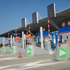 Peaje de autopista con carriles de pago y señalización. Así como funciona vía T, con barreras y luces indicadoras.