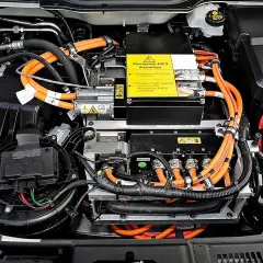 Vista detallada de las partes de un coche eléctrico, mostrando cables naranjas de alta tensión, componentes electrónicos y un ventilador.