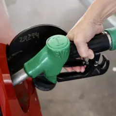Mano repostando un coche rojo con una manguera de combustible verde. El futuro de los coches diésel aún depende de la gasolina.