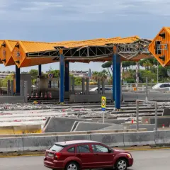Peaje en construcción cerca de Barcelona. Estructuras naranjas y azules, escombros y coches circulan.