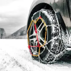 Rueda de coche con cadenas para garantizar la viabilidad invernal en un paisaje nevado.