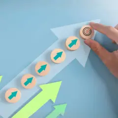 Flechas verdes ascendentes y discos de madera con flechas apuntando a un objetivo, simbolizando el progreso en las áreas de servicio AP7.