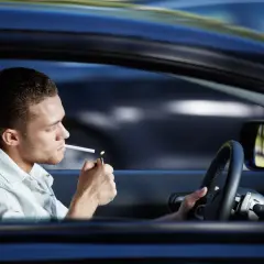 Joven enciende cigarrillo mientras se puede fumar conduciendo.