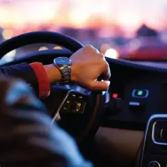 Persona conduce de noche en EE.UU., atento al **límite de velocidad** y al tráfico urbano.
