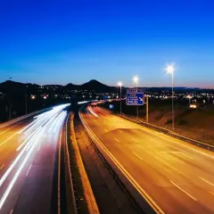 Autopista nocturna con estelas de luz de vehículos, reflejando la **estrategia seguridad vial 2030** para un futuro más seguro.