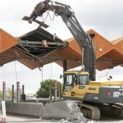 Excavadora derribando el peaje de Cubelles. La estructura naranja se desmorona mientras la máquina trabaja.