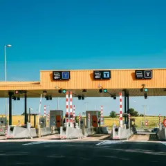 Peaje en la a6 autovía, con barreras rojas y blancas, señales de tráfico y un cielo azul despejado.