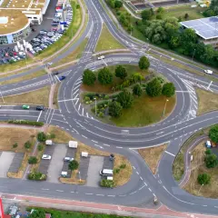 Vista aérea de una rotonda con tráfico, rodeada de edificios y aparcamientos. Un lugar ideal en una autopista donde puede realizar un cambio de sentido.