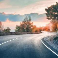 Carretera sinuosa al atardecer. Señal de prohibido adelantar en curvas.
