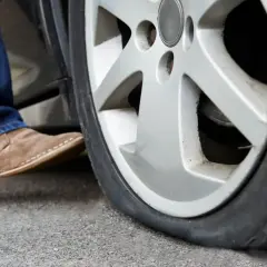 Un neumático runflat pinchado, con un pie saliendo del coche.