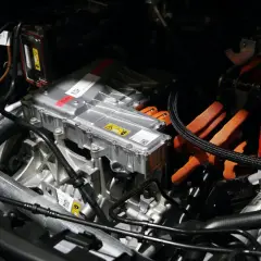 Detalles del motor de un coche eléctrico, listo para su revisión. Cables naranjas de alta tensión y componentes metálicos.