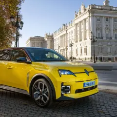 Coche amarillo con etiqueta ECO, aparcado frente a un edificio histórico. Los coches con etiqueta eco pagan impuesto de circulación, pero este parece disfrutar de un día soleado.