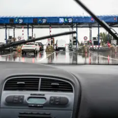 Fila de coches en un día lluvioso en los peajes de España. El coche se acerca a las cabinas de pago.