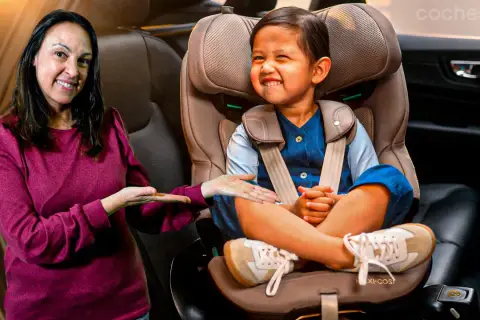 Una mujer sonríe mientras señala a un niño feliz sentado en su silla de coche. ¡Los niños en el coche están seguros y contentos!