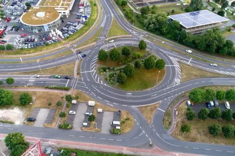 Vista aérea de una rotonda con tráfico, rodeada de edificios y aparcamientos. Un lugar ideal en una autopista donde puede realizar un cambio de sentido.