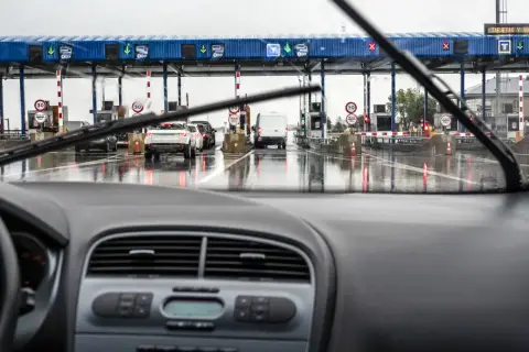 Fila de coches en un día lluvioso en los peajes de España. El coche se acerca a las cabinas de pago.
