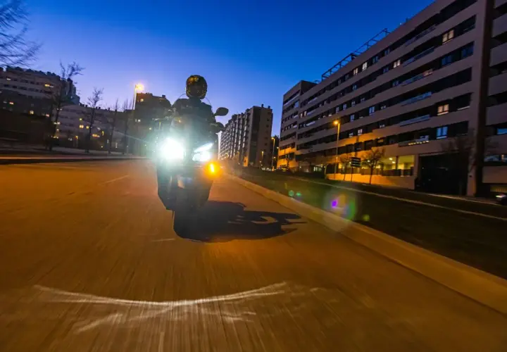 Motociclista con luces potentes de noche. Para no deslumbrar, es importante ajustar la altura de los faros y usar luces de baja intensidad cuando sea posible.