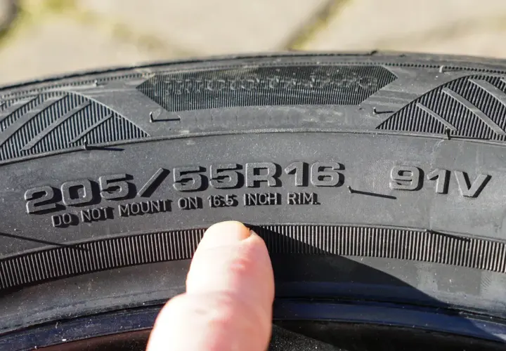 Dedo señala inscripción en neumático: 205/55R16 91V. ¡Cuidado con la caducidad neumáticos!