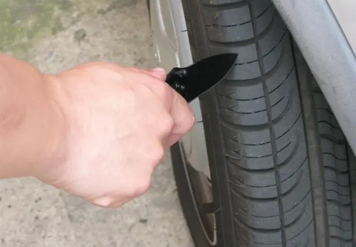 Mano con navaja revisando la banda de rodadura de un neumático, para saber si tengo una rueda pinchada.