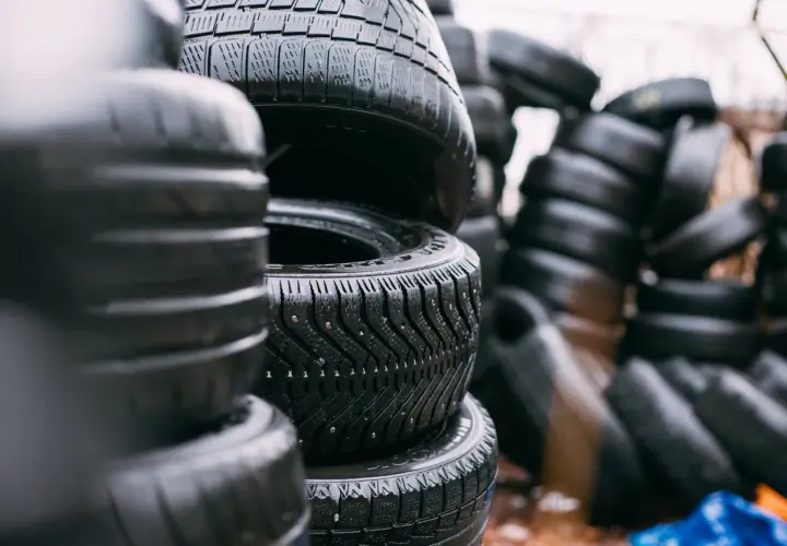 Montón de neumáticos mojados apilados. ¿Cuánto pesa un neumático? La imagen muestra una pila de neumáticos de coche, algunos con clavos para el invierno.