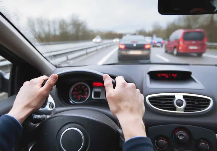 Manos al volante en carretera con tráfico. Mantener una distancia de frenado segura depende de la atención.