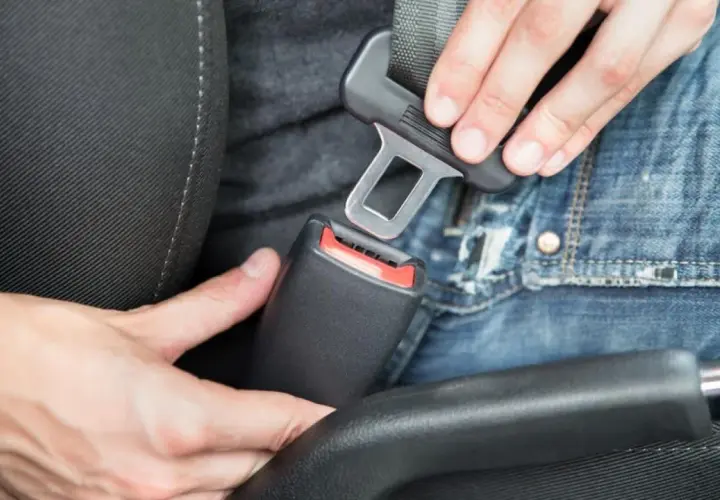 Persona abrochando el cinturón de seguridad en un coche. En un turismo es obligatorio utilizar los cinturones de seguridad.