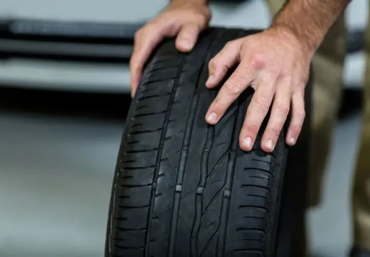 Manos sostienen una rueda de coche. Averigua cuanto se tarda en cambiar una rueda.