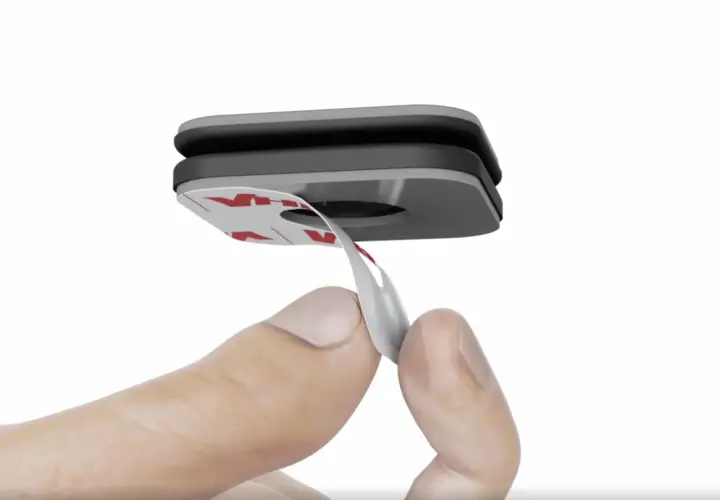 Dedo retirando el protector de un adhesivo para un dispositivo de vía-t gratis.