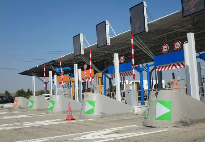 Peaje de autopista con carriles de pago y señalización. Así como funciona vía T, con barreras y luces indicadoras.