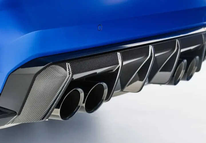 Detalle de escape cuádruple de coche deportivo azul, con difusor de fibra de carbono. Un vistazo a las emisiones de CO2 de los coches.