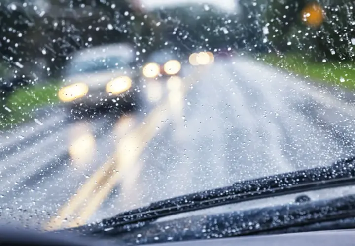 Si conduciendo le sorprende una lluvia torrencial, el parabrisas se llena de gotas. Luces de otros coches se difuminan en la carretera mojada.