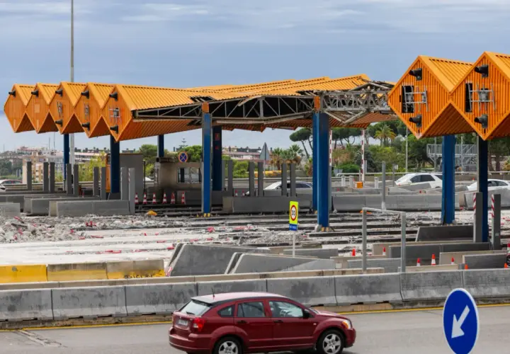 Peaje en construcción cerca de Barcelona. Estructuras naranjas y azules, escombros y coches circulan.