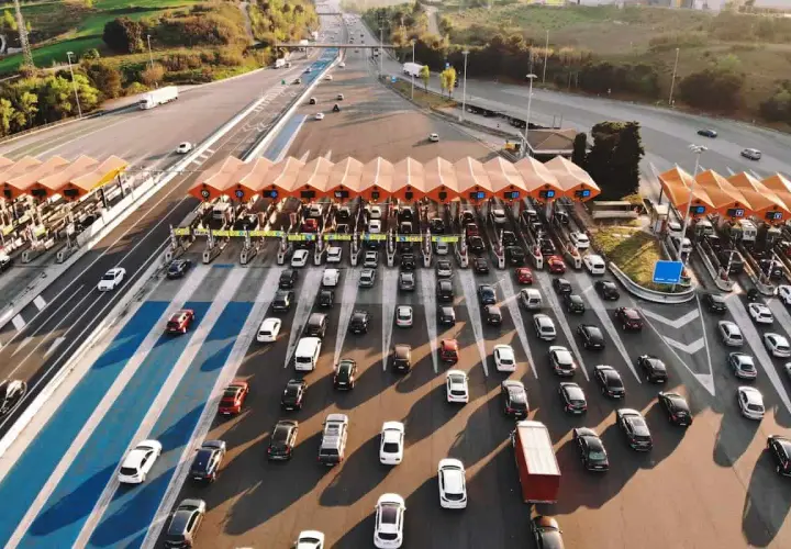 Larga fila de coches en un peaje, creando un gran atasco. Los vehículos esperan pacientemente su turno para pasar.