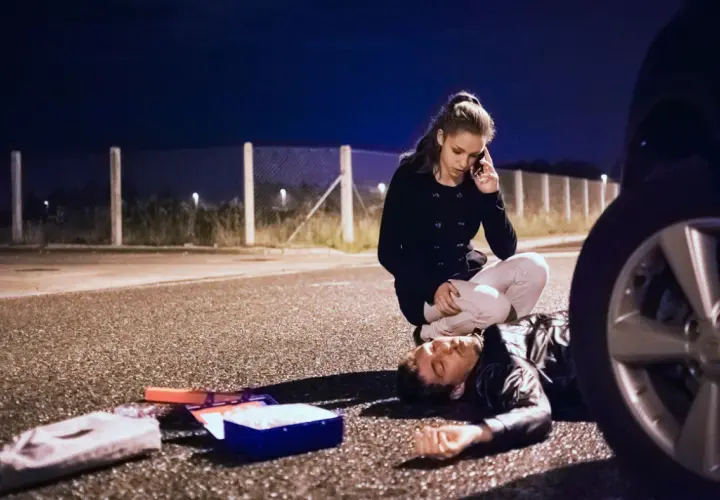 Una mujer llama a emergencias junto a un hombre tendido en la carretera. A su lado, un botiquín abierto. ¿Qué significa pas? ¿Una vida en peligro?