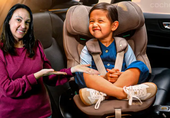 Una mujer sonríe mientras señala a un niño feliz sentado en su silla de coche. ¡Los niños en el coche están seguros y contentos!