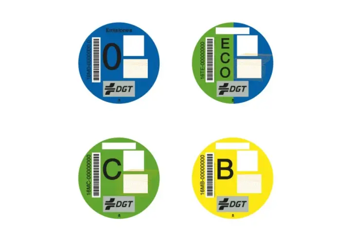 Cuatro etiquetas medioambientales circulares de la DGT: "0" (azul), "ECO" (verde y azul), "C" (verde) y "B" (amarillo).