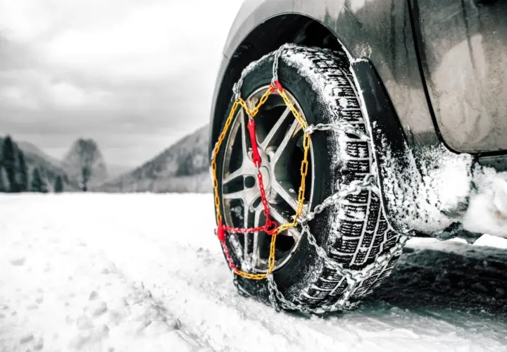Rueda de coche con cadenas para garantizar la viabilidad invernal en un paisaje nevado.