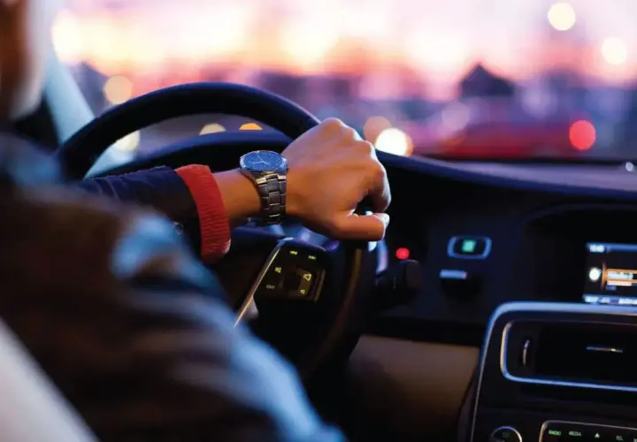 Persona conduce de noche en EE.UU., atento al **límite de velocidad** y al tráfico urbano.