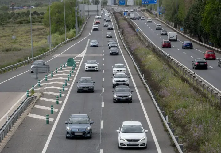 Tráfico en autopista, coches circulando. ¿Cuánto vale el peaje de Madrid? La carretera se ve con vegetación a los lados.